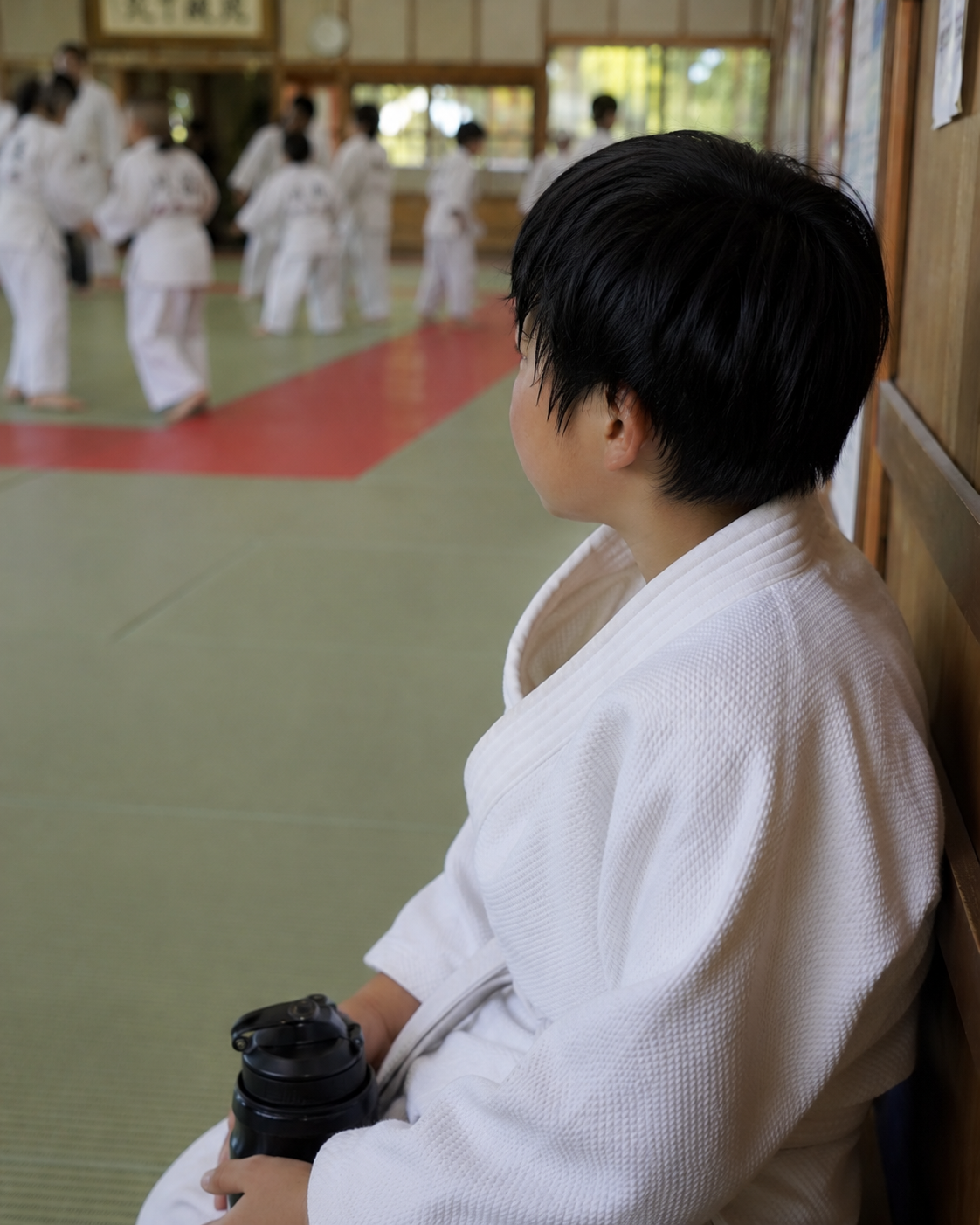 道場で稽古の合間に休む少年